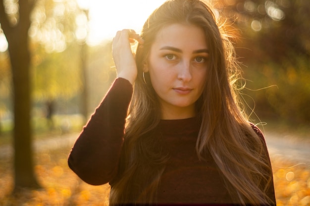 Portrait of beautiful woman and looking away at park during sunset