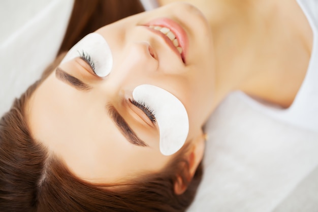 Portrait of a beautiful woman making herself new eyelashes in a beauty studio