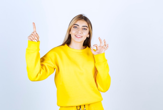 Portrait of beautiful woman model pointing up and doing ok gesture