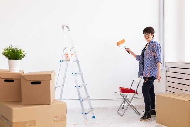 Portrait of beautiful woman painting wall in a new apartment