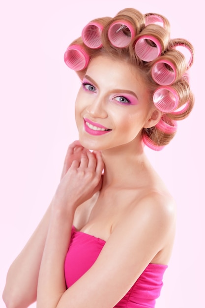 Portrait of Beautiful  woman in pink dress with hair curlers in studio