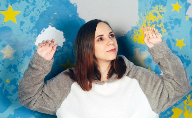 Portrait of beautiful woman in plush hoodie dancing on background of colorful bright wall