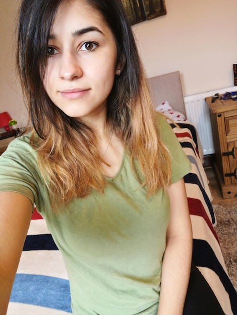 Photo portrait of beautiful woman sitting on bed at home