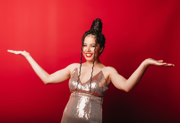 Portrait of a beautiful woman smiling standing presenting a product holding something on palm bayside studio shot isolated on a red background with space to copy female hand gesture