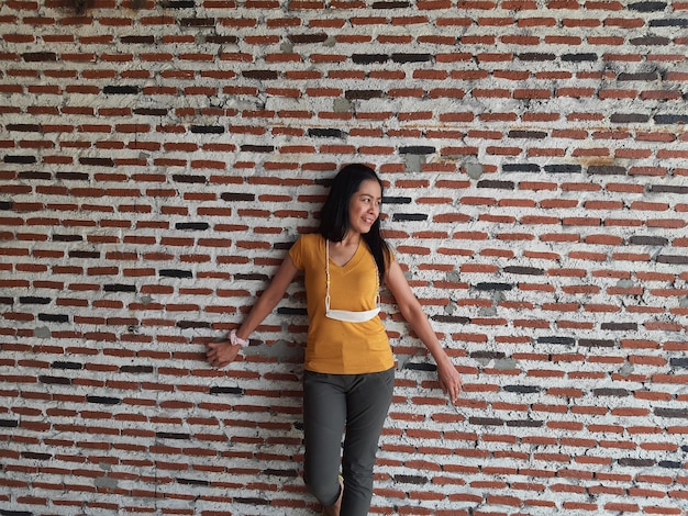 Photo portrait of beautiful woman standing against brick wall