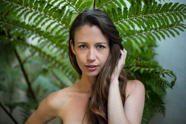 Portrait of beautiful woman standing outdoors against green plants