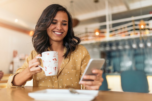 Portrait of beautiful woman using mobile in coffee shop.