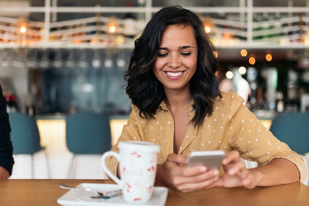 Portrait of beautiful woman using mobile in coffee shop.