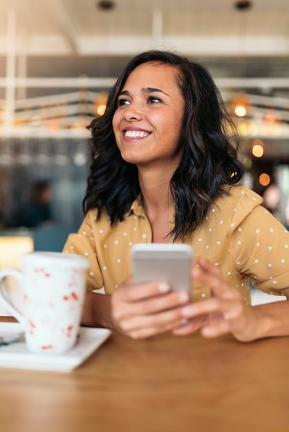 Portrait of beautiful woman using mobile in coffee shop.