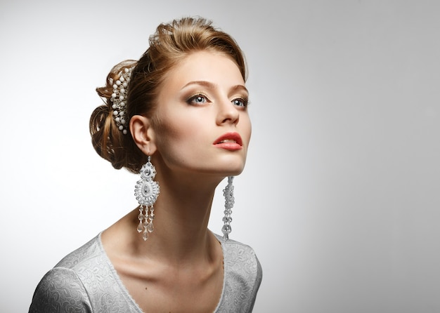 Portrait of a beautiful woman in a white dress and big earrings.