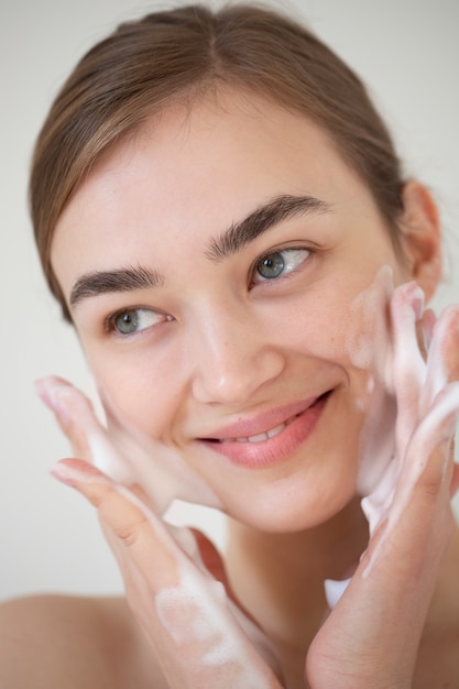 Portrait of beautiful woman with clear skin washing face with foam cleanser