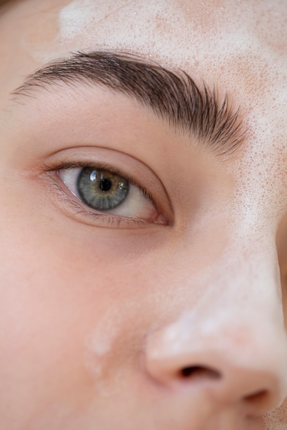 Portrait of beautiful woman with clear skin washing face with foam cleanser