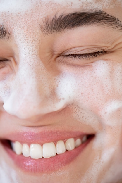 Portrait of beautiful woman with clear skin washing face with foam cleanser