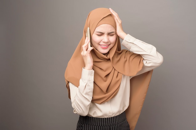 Portrait of beautiful woman with hijab using cellphone on gray background