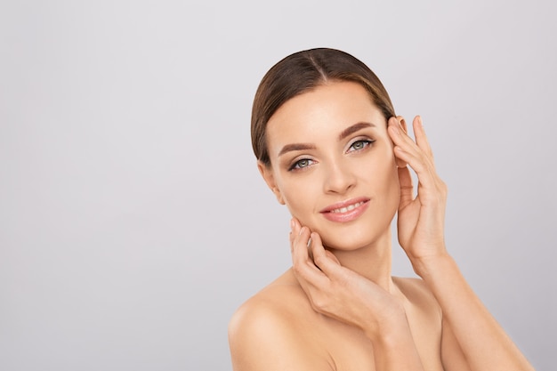 Portrait of beautiful woman with natural make up touching her face. 