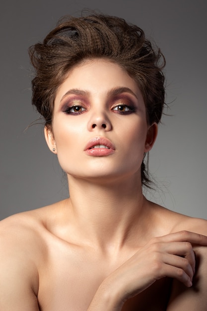 Portrait of beautiful woman with romantic red and gold smokey eyes makeup