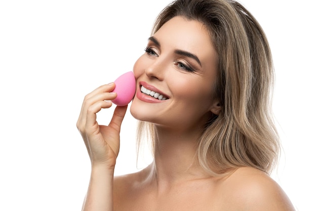 Portrait of beautiful woman with a smooth skin holding makeup sponge on white background