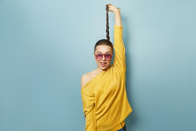 Portrait of a beautiful woman  with sunglasses holding to the hair. isolated blue background