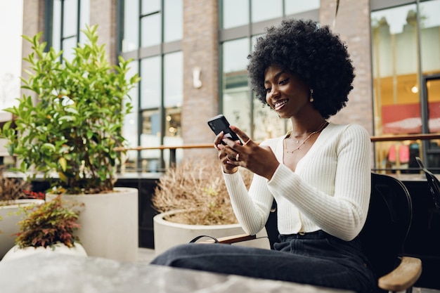 Portrait of a beautiful young african woman using her cellphone in a cafe