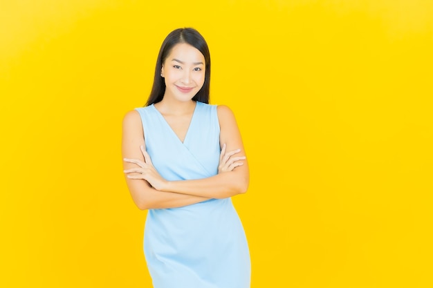 Portrait beautiful young asian woman smile with action on yellow color wall