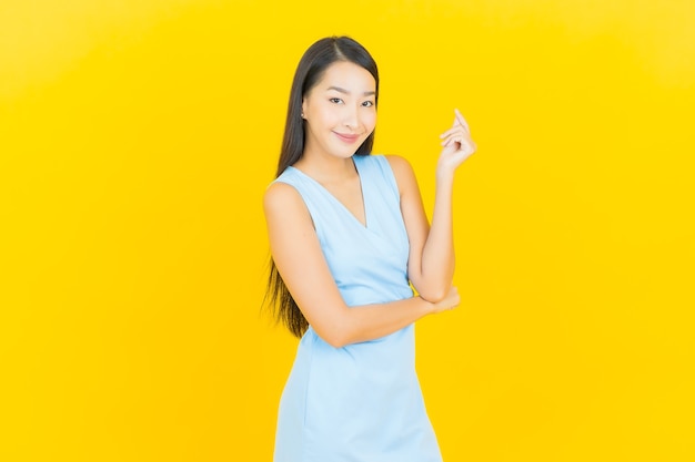 Portrait beautiful young asian woman smile with action on yellow color wall