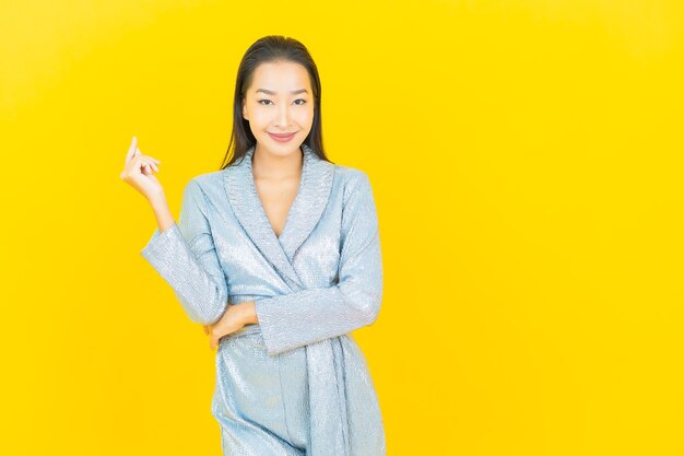 Portrait beautiful young asian woman smile with action on yellow wall