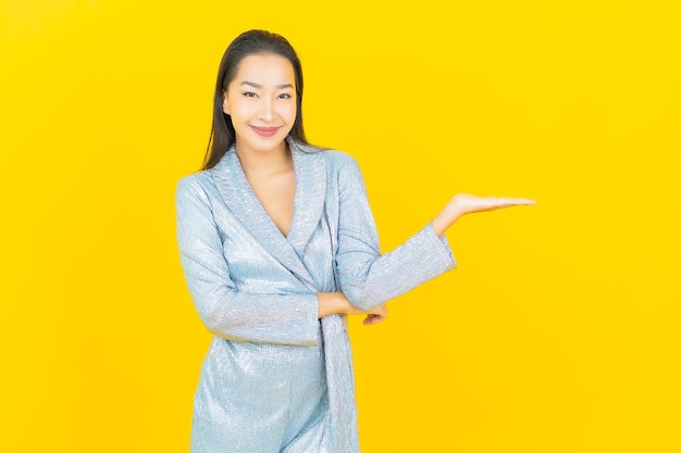 Portrait beautiful young asian woman smile with action on yellow wall