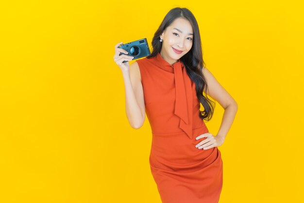 Portrait beautiful young asian woman use camera on yellow