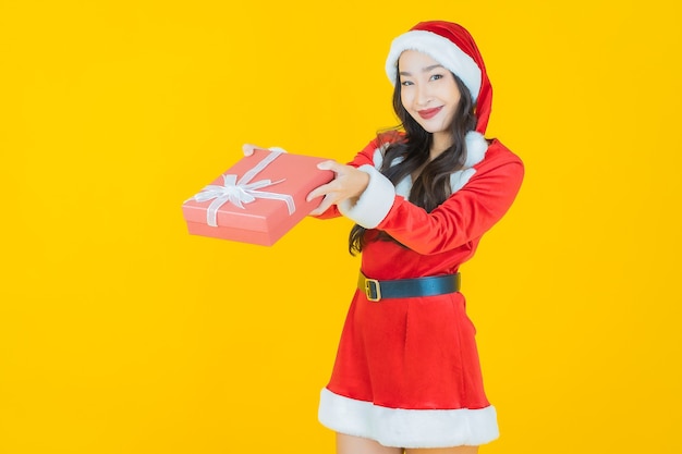 Portrait beautiful young asian woman wear christmas costume with red gift box on yellow