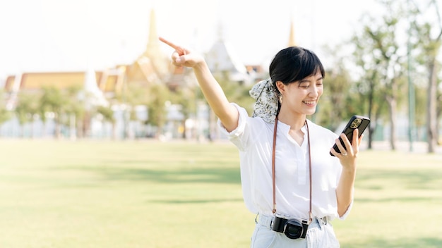 Portrait beautiful young asian woman with smartphone on summer holiday vacation trip with the grand palace in a background at Bangkok Thailand