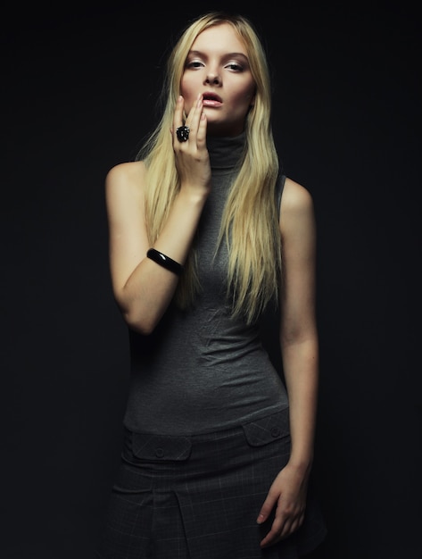 Portrait of beautiful young blonde girl over dark background. Fashion photo.