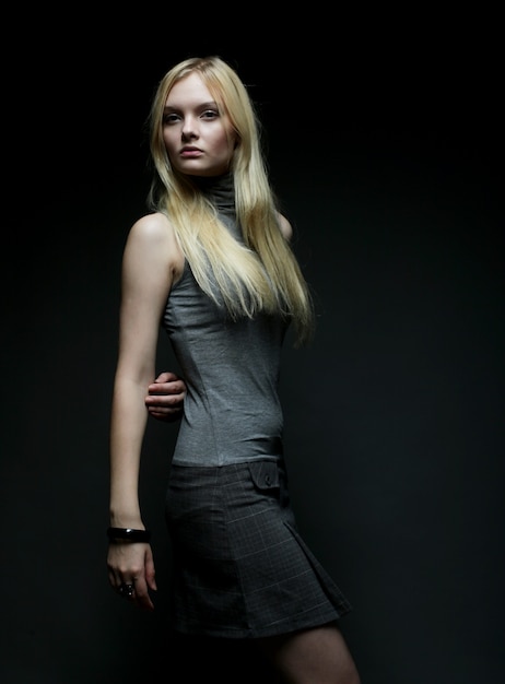 Portrait of beautiful young blonde girl over dark. Fashion photo.