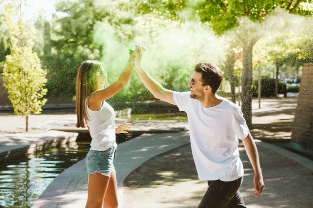 Portrait of beautiful young couple playing in the park on holi color festival.