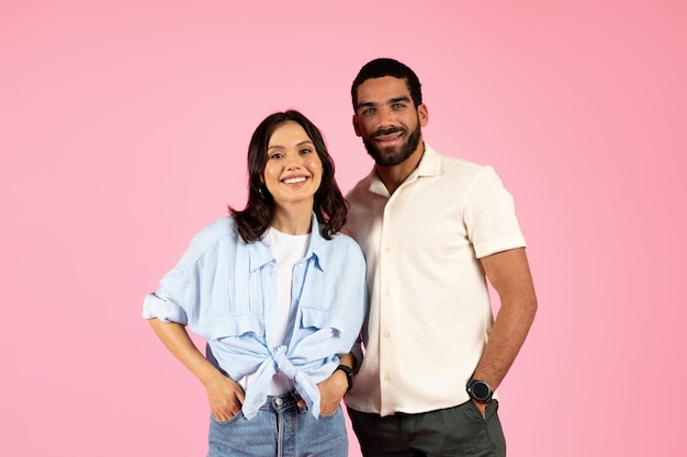 Portrait of beautiful young couple posing together on pink