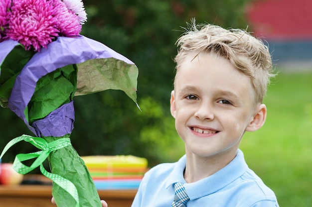 Portrait of a beautiful young first-grader with red apple on books in a festive school uniform