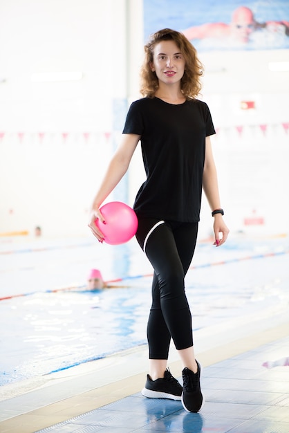 Portrait of a beautiful young girl coach near the swimming pool.