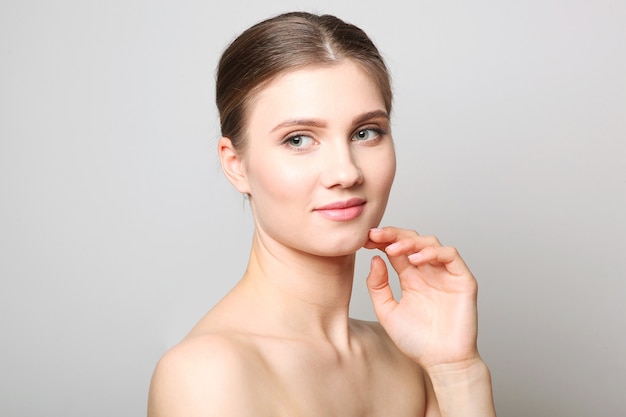 Portrait of a beautiful young girl with nude makeup on a light background