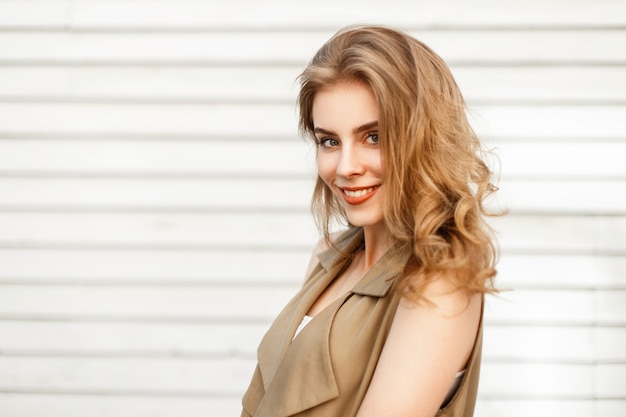 Portrait of a beautiful young girl with a smile and hairstyle near a wooden wall