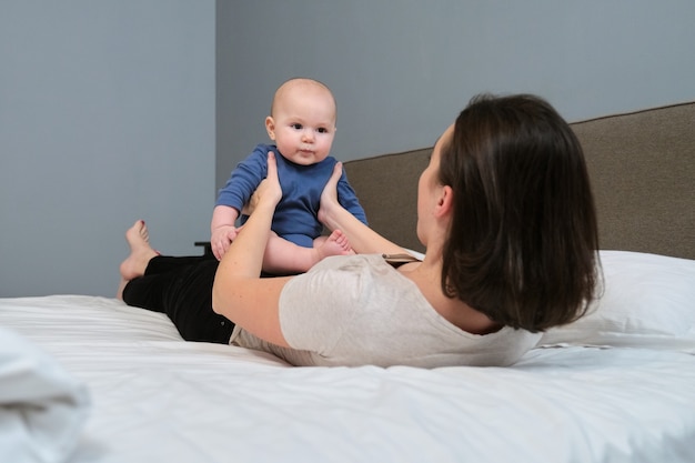 Portrait of beautiful young mother and her baby 7 month old son, parent and baby lying in bed together