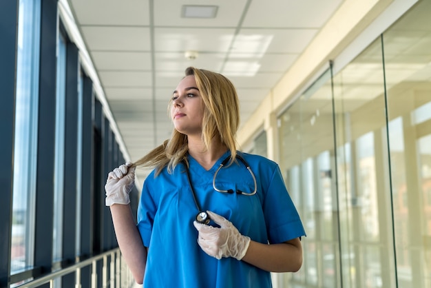 Portrait of beautiful young nurse in blue inofrm in clinic. healthcare