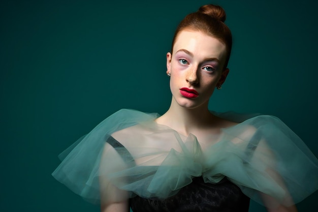 Portrait of a beautiful young redhead woman in black dress Studio shot