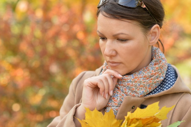 Portrait of beautiful young sad woman in autumnal park