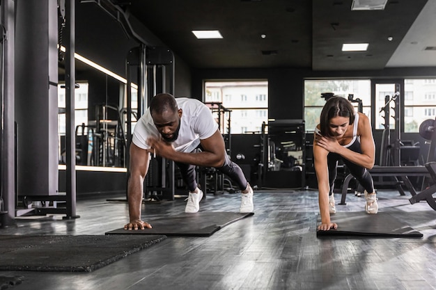 Portrait of beautiful young sports couple african man and caucasian woman on a plank position