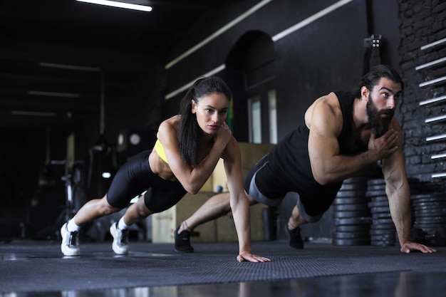 Portrait of beautiful young sports couple on a plank position.