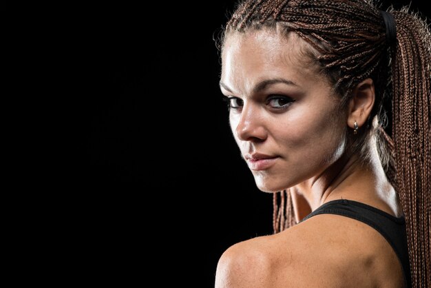 Photo portrait of a beautiful young sportswoman with dreadlocks on a black background