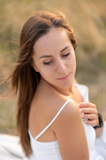 Portrait of a beautiful young tender brunette girl in a white sundress, in nature.