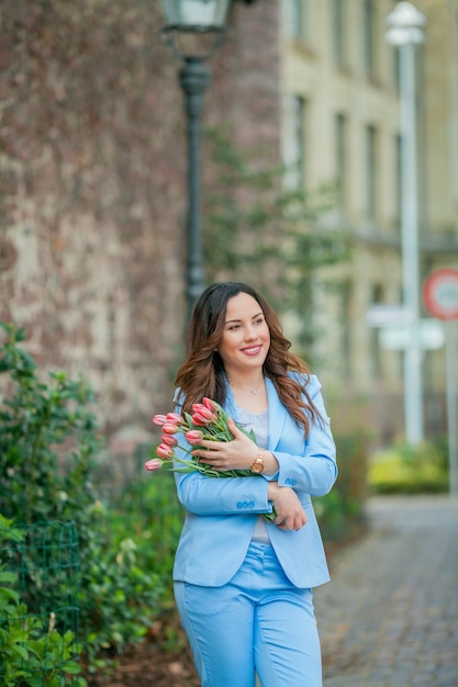 Portrait of a beautiful young woman in a blue suit with a bouquet of tulips