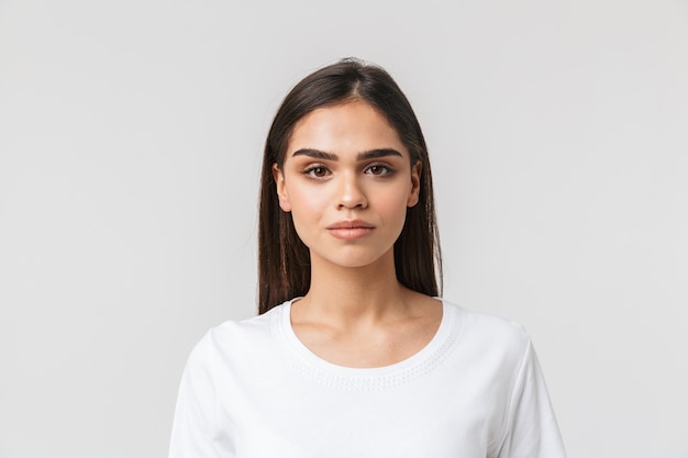 Portrait of a beautiful young woman casualy dressed standing isolated on white, looking at camera