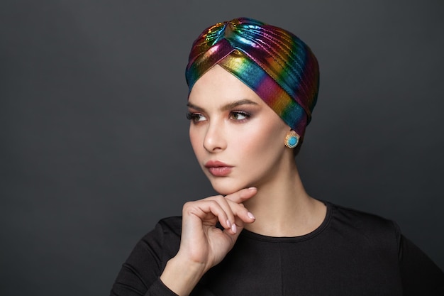 Portrait of a beautiful young woman in a colorful turban on her head and golden jewelry earring