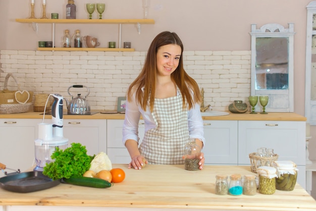 Portrait of beautiful young woman cooking in the kitchen. Young Woman Cooking. Healthy Food - Vegetable Salad.